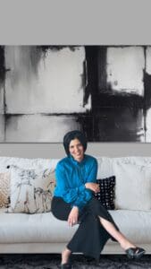 Angel sitting on a couch in a blue shirt.